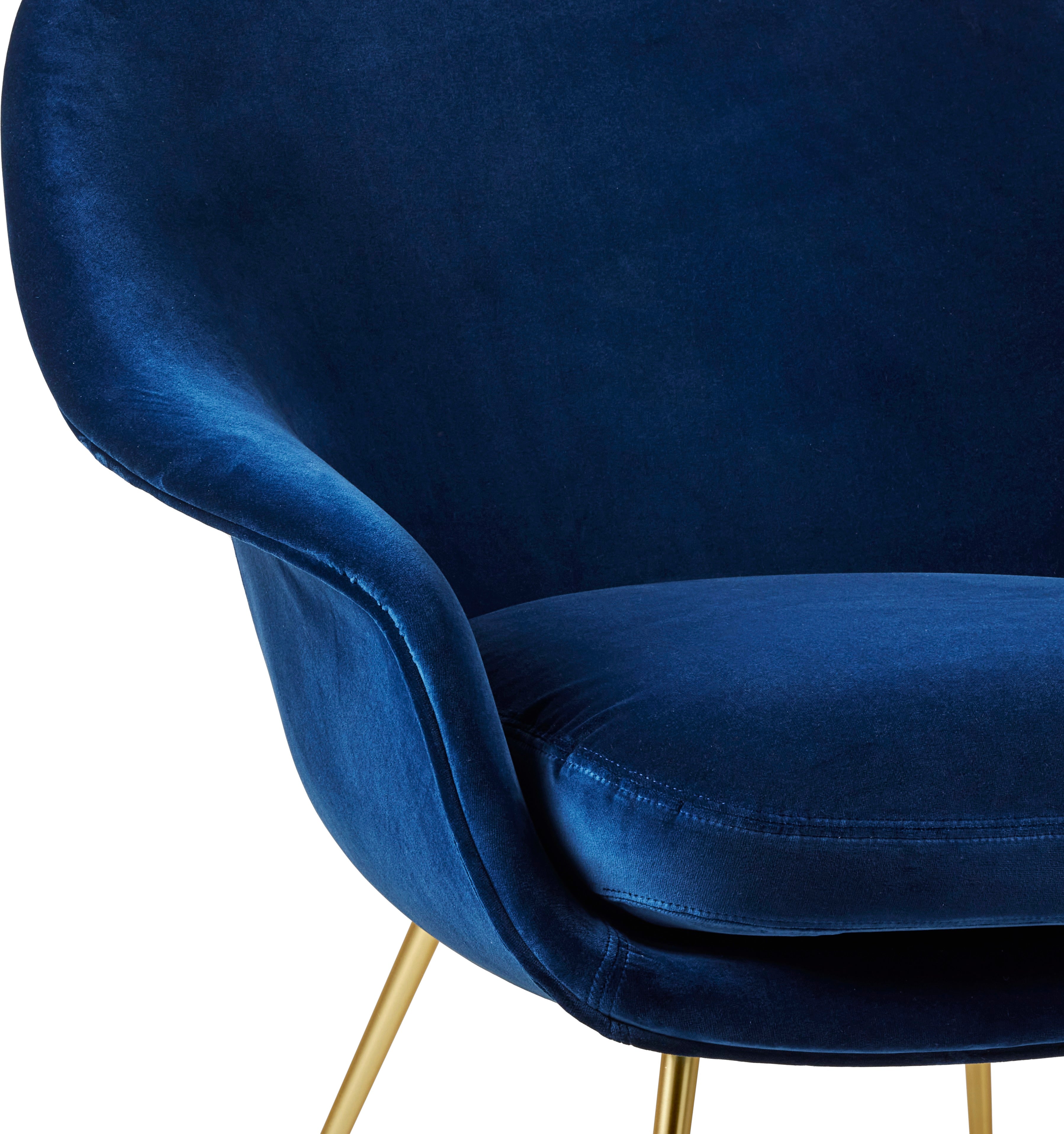 Upholstered BAT armchair with a gold base