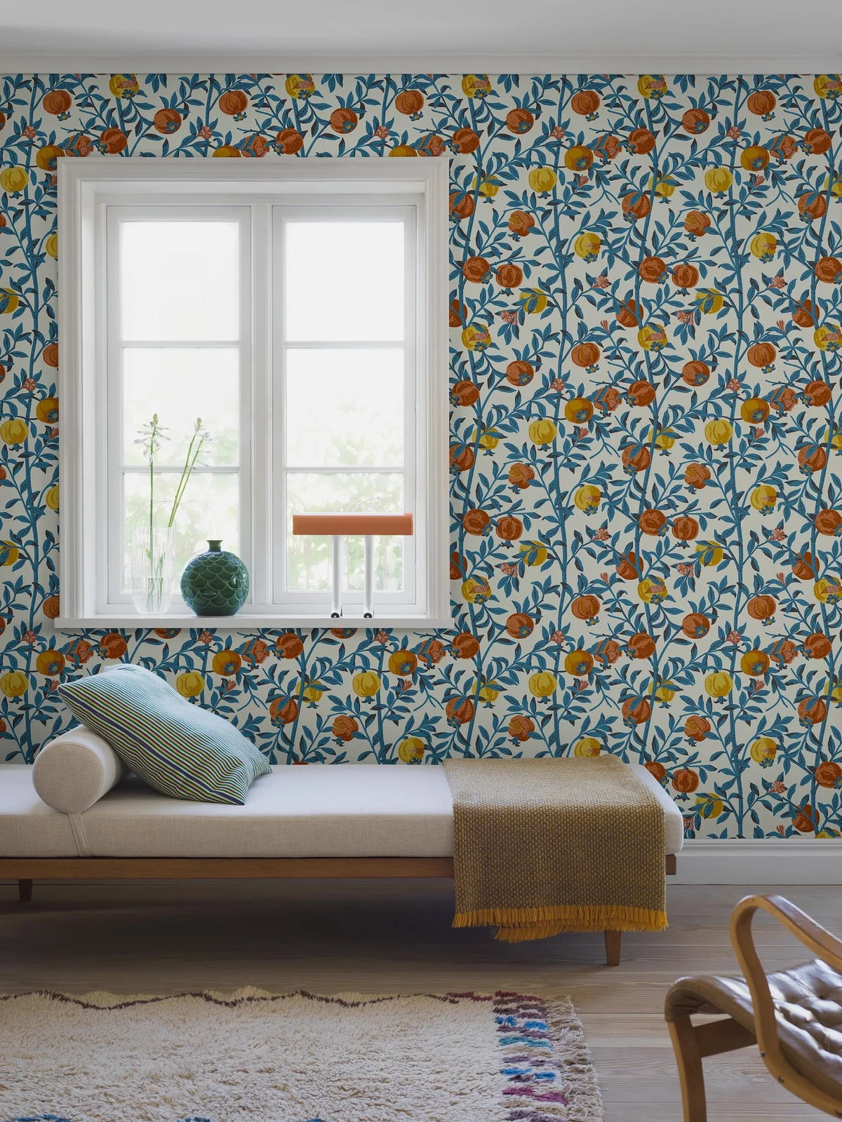 Wallpaper with a botanical pattern of pomegranates in white with blue and orange