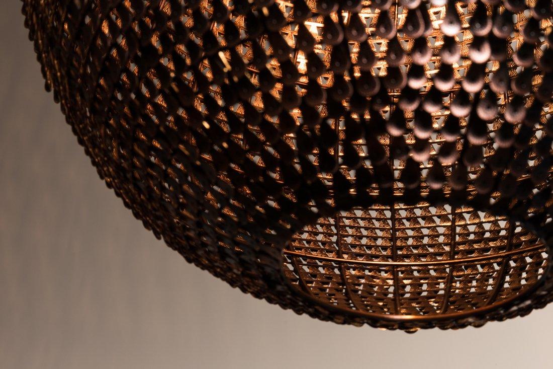 Shiny Cooper lamps were created from hundreds of small copper scales, which were additionally discolored at hot temperatures. Copper scales have been manually placed on the lamp, thanks to which each model has a unique shape and appearance. The lamp gives an amazing effect of light movement, bouncing off tiny copper tiles.